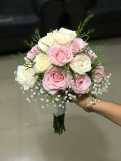 a bouquet of pink and white roses in someone's hand