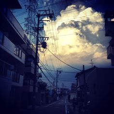 the sun is setting behind power lines in an urban area with buildings and telephone poles