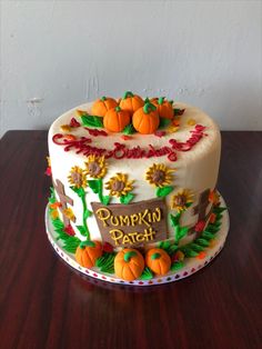 a decorated cake sitting on top of a wooden table covered in frosting and pumpkins