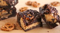 several pieces of brownie with chocolate and pretzel toppings on a cutting board