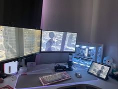 three computer monitors sitting on top of a desk next to a keyboard and monitor screen