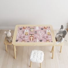 two stuffed animals sitting on stools in front of a table with a pink background