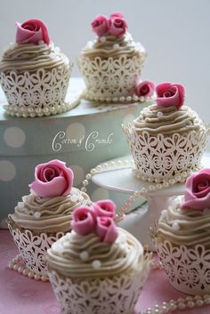 several cupcakes with pink frosting and roses on them are sitting next to each other