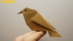 a hand is holding an origami bird