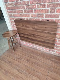 a wooden table sitting on top of a hard wood floor next to a brick wall