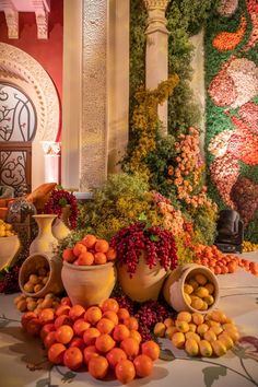 there are many vases that have fruit in them on the table and one is full of oranges