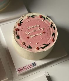 a pink birthday cake sitting on top of a white box