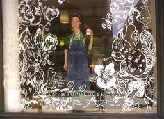 a woman standing in front of a window holding a cup