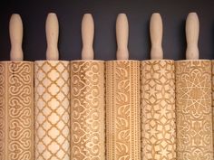 four wooden handles are lined up against the wall with intricate designs on them, along with other decorative items