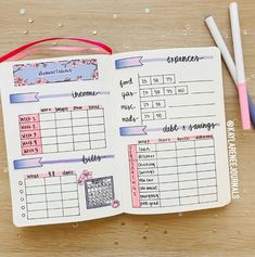 an open planner book sitting on top of a wooden table next to two pencils