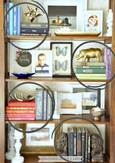 a bookshelf filled with lots of books and assorted pictures on top of it