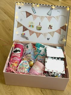 an open box filled with various items on a wooden floor next to a string of lights