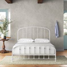 a white bed sitting in a bedroom on top of a hard wood floor next to a window