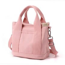 a pink handbag is sitting on a white surface with a strap around the handle