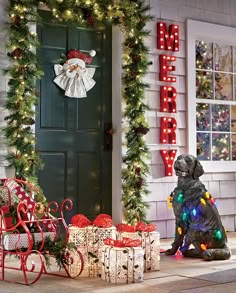 a dog sitting on the ground next to christmas decorations and presents in front of a door