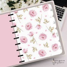 a notebook with pink roses on it next to a laptop