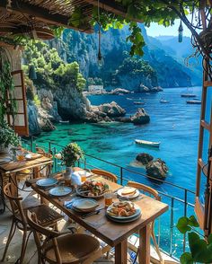 an outdoor dining area overlooking the ocean and boats in the water, with wooden tables and chairs