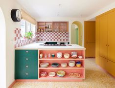 a kitchen with an island and colorful cabinets in the center, filled with plates and bowls