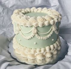 a three tiered cake with white icing on a sheet covered tablecloths