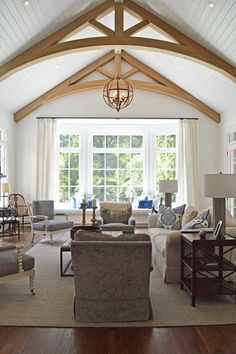 a living room filled with furniture and a chandelier hanging from the ceiling in front of a window