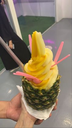 a person holding up a pineapple ice cream with strawberries and mango slices on top