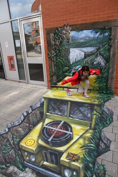 a painting on the side of a building depicting a jeep with a man sitting on it