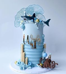 a three tiered blue cake with gold decorations on top and under the sea theme