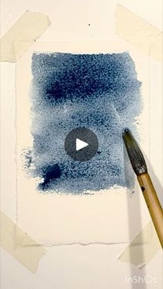 a paintbrush is being used to create a blue painting with white paper on the wall