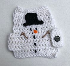 a crocheted snowman with a black hat and scarf on it's lap