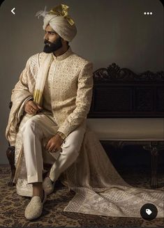 a man sitting on top of a bench wearing a turban and white pants