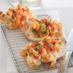 two pieces of bread with various toppings on a cooling rack next to a knife and fork