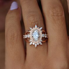 a woman's hand with an engagement ring on it and the center stone is surrounded by diamonds