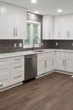 an empty kitchen with white cabinets and wood floors