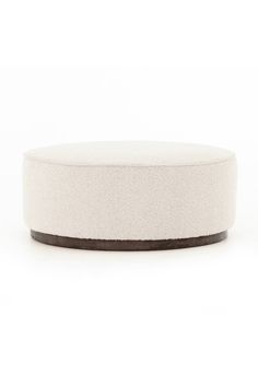 a white round ottoman sitting on top of a table