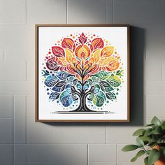 the colorful tree is hanging on the wall next to a potted plant in front of it