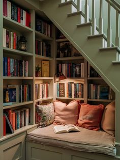 a bookshelf filled with lots of books next to a stair case