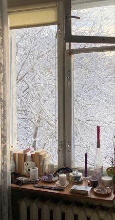 a window with frosted trees outside in front of it and books on the windowsill