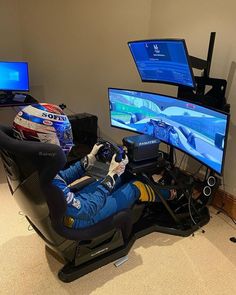 a person sitting in a chair playing a video game on a computer monitor and two monitors