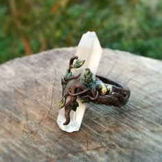 a ring with two small figurines sitting on top of a piece of wood