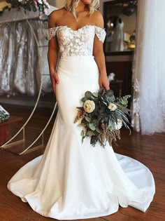 a woman in a white wedding dress holding a bouquet and standing on a wooden floor