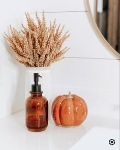 a bathroom counter with a soap dispenser and two pumpkins