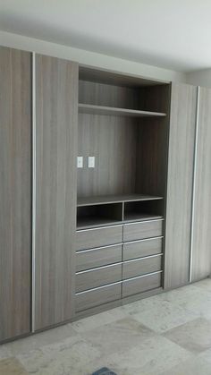 an empty room with some wooden cabinets and drawers on the wall, in front of a tiled floor