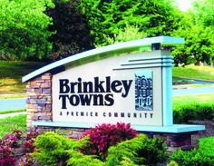 the sign for brinkley townships apartments in front of some trees and bushes with purple flowers