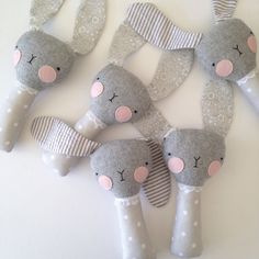 four stuffed animals made out of gray and white material with pink noses, ears and tails