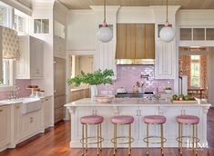 a kitchen with white cabinets, pink stools and wood flooring is seen in this image