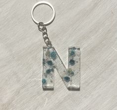 the letter n is made out of glass and has blue flowers on it's side