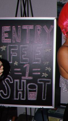 a woman with red hair standing in front of a sign that says entry fee shot