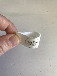 a hand holding a white wristband with the word madesoi written on it