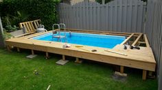 an above ground pool surrounded by wooden decking and lawn furniture in a backyard area