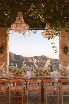 an outdoor dining area with tables, chairs and chandelier hanging from the ceiling